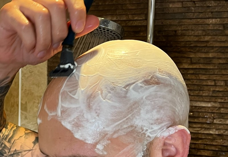 Shaving head in shower against the grain